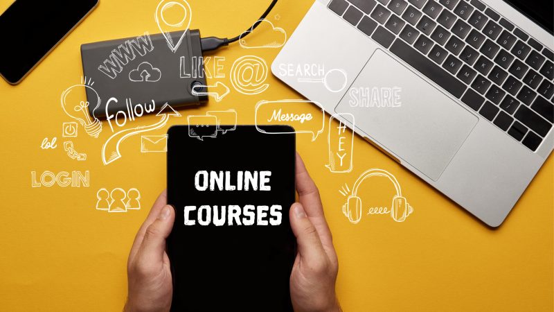 cropped view of man holding digital tablet with online courses illustration